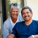 Pareja hispana mayor sonriendo con tranquilidad sabiendo que un préstamo sobre el valor de la vivienda cubrirá sus facturas médicas.