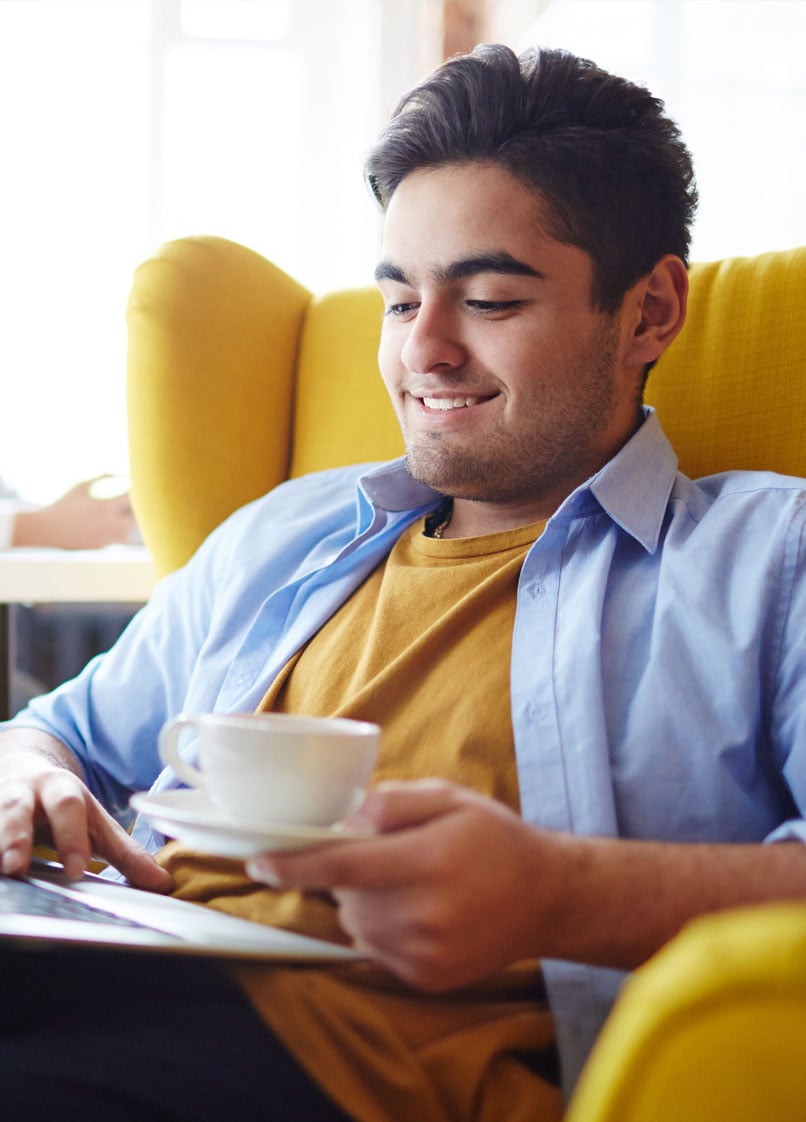 Hombre considerando un préstamo personal en una cafetería en su computadora portátil.