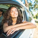 Mujer mirando desde su auto nuevo financiado por un préstamo para automóviles de Alianza