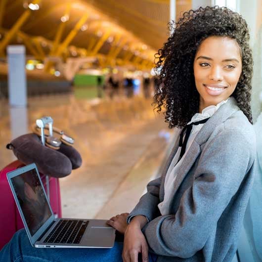 Travel-credit-card-rewards-helps-this-business-woman-sitting-on-floor-of-airport-travel-the-world.