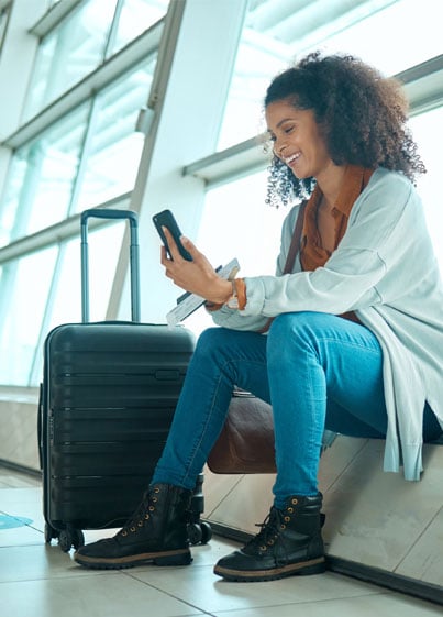 Woman-using-her-travel-credit-card-points-to-fly-while-sitting-at-airport-on-her-cell-phone.