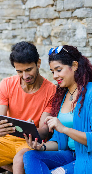 Couple-researching-ploc-vs-personal-loan-in-front-of-brick-wall-together.