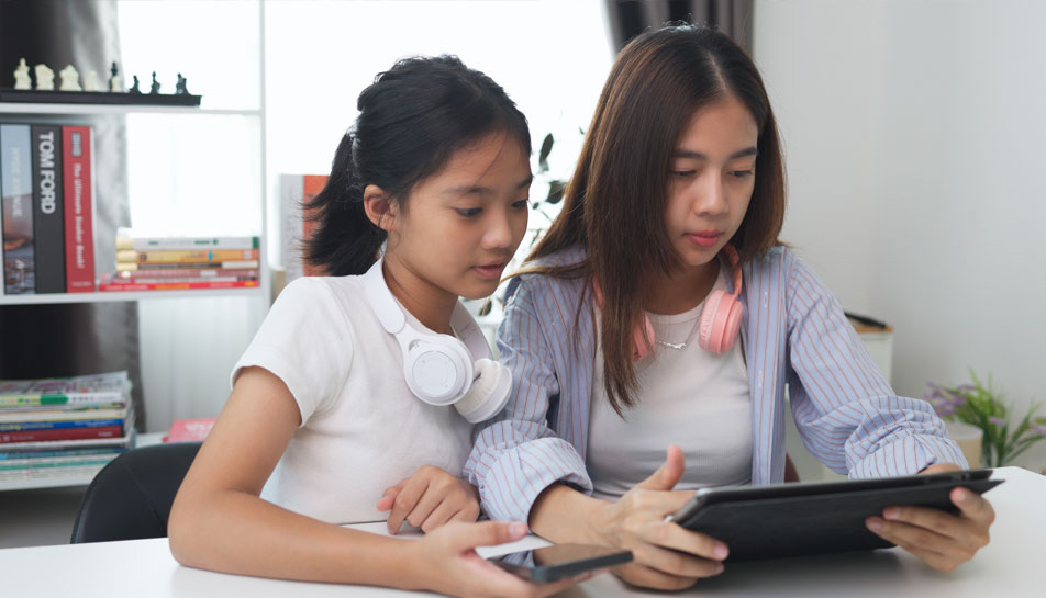 Teens-budgeting-together-as-they-look-at-their-credit-union-financial-accounts-on-an-ipad-and-phone.