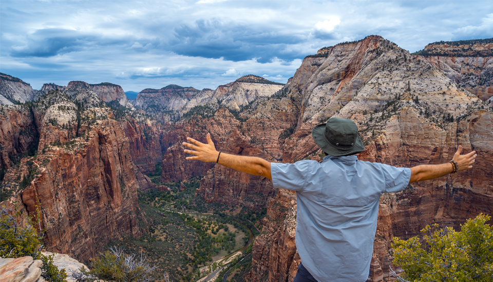 Man-used-a-personal-loan-for-vacation-and-is-now-enojying-the-view-with-arms-wide-of-national-park.