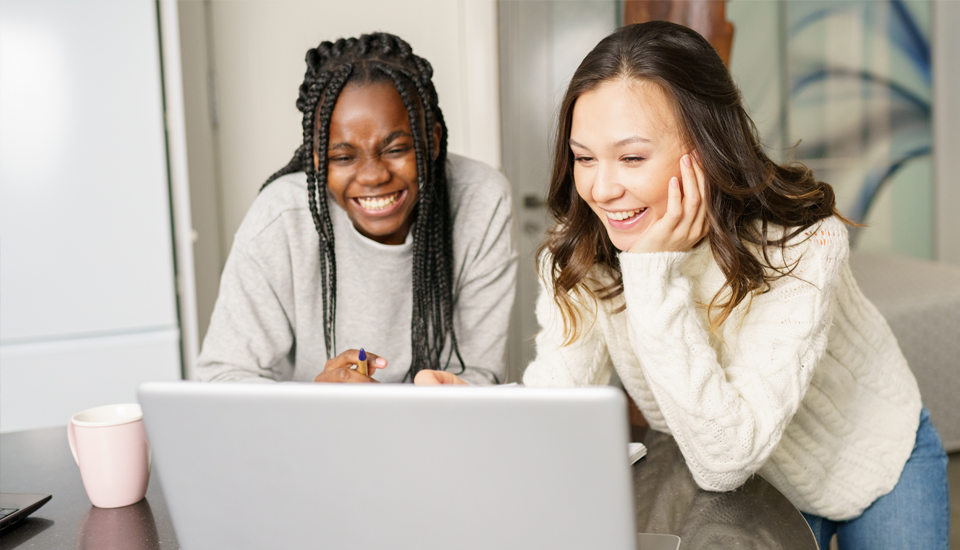 Women-couple-working-on-their-vacation-budget-together-on-a-laptop-smiling.